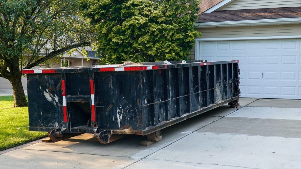 a large black dumpster in front of a house