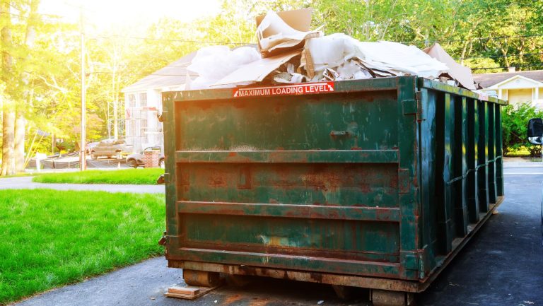 A green roll off bin full of garbage